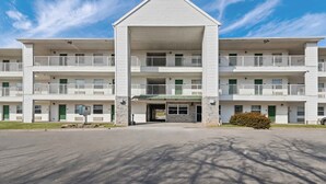 A multi-story motel with a central entrance, balconies, and a sign indicating an office. - Birch Hill Suites Kansas City – Independence (Independence)