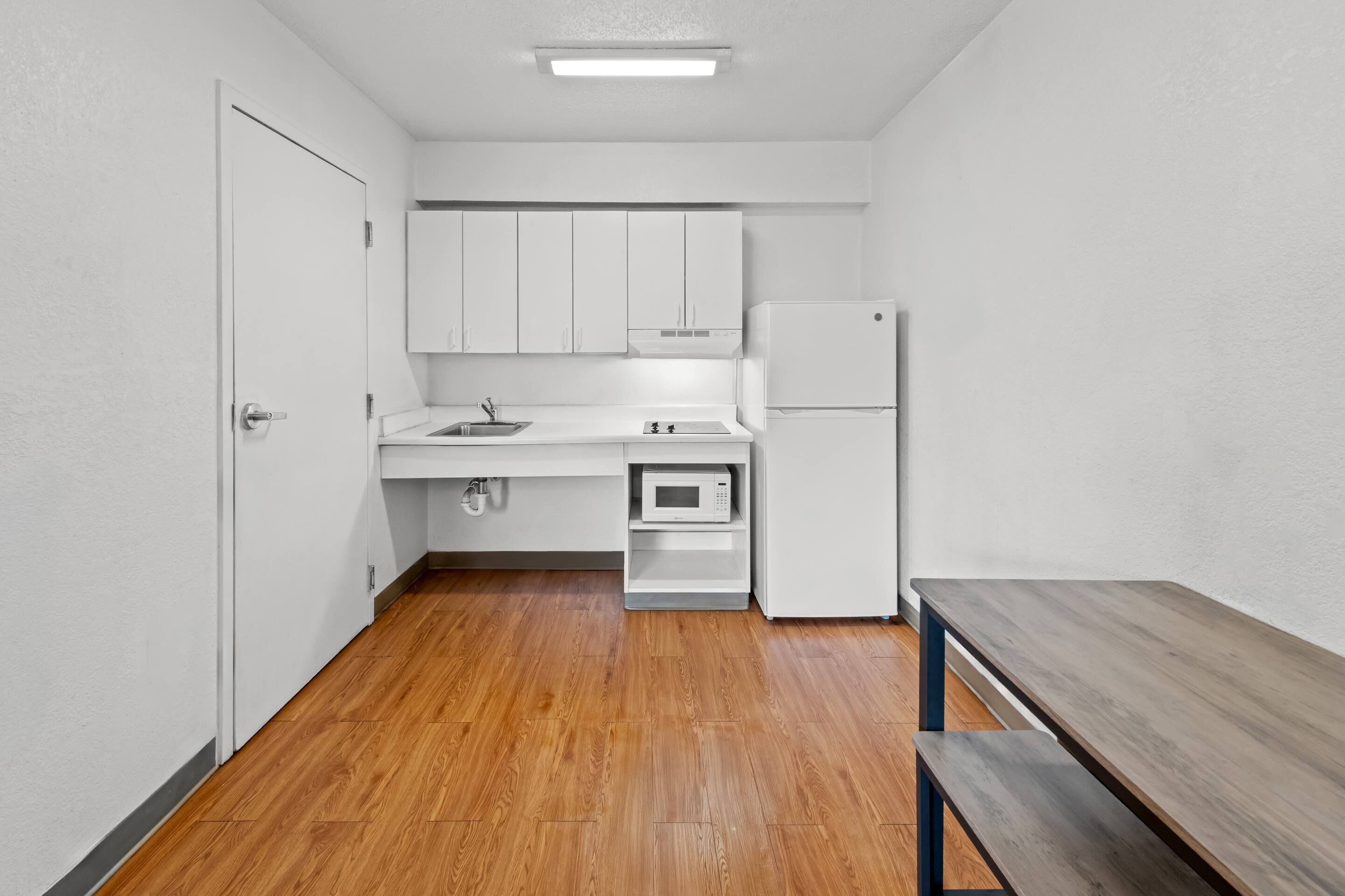 A compact kitchen with white cabinets, a microwave, and a double-door refrigerator.
