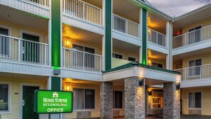 A multi-story hotel with a green and white color scheme, featuring balconies and a stone facade. - HomeTowne Studios By Red Roof Eugene - Springfield (Springfield)
