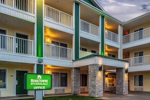 A multi-story hotel with a green and white color scheme, featuring balconies and a stone facade. - HomeTowne Studios By Red Roof Eugene - Springfield (Springfield)