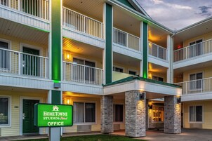 A multi-story hotel with a green and white color scheme, featuring balconies and a stone facade.
