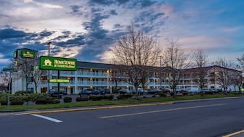 A motel with a sign indicating nightly and weekly rates, a parking lot, and a building with a flat roof.