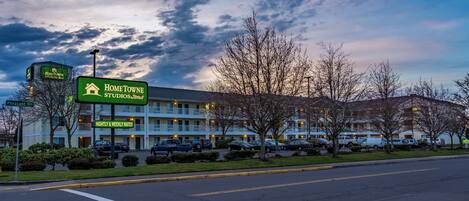 A motel with a sign indicating nightly and weekly rates, a parking lot, and a building with a flat roof.