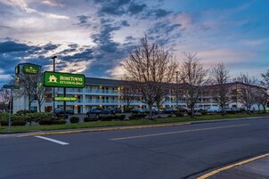 Un motel con un cartel que indica tarifas por noche y semanales, un estacionamiento y un edificio con techo plano.