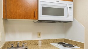 A kitchen with a built-in microwave, a stainless steel sink, and a granite countertop. - HomeTowne Studios By Red Roof Eugene - Springfield (Springfield)