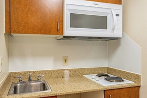 A kitchen with a built-in microwave, a stainless steel sink, and a granite countertop. - HomeTowne Studios By Red Roof Eugene - Springfield (Springfield)