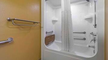 Un baño con bañera, ducha y retrete. Se han instalado barras de apoyo en las paredes.