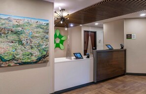 A reception desk with a digital screen, a phone, and a sign indicating check-out procedures. - Extended Stay America Premier Suites Seattle Bellevue Downtown (Bellevue)