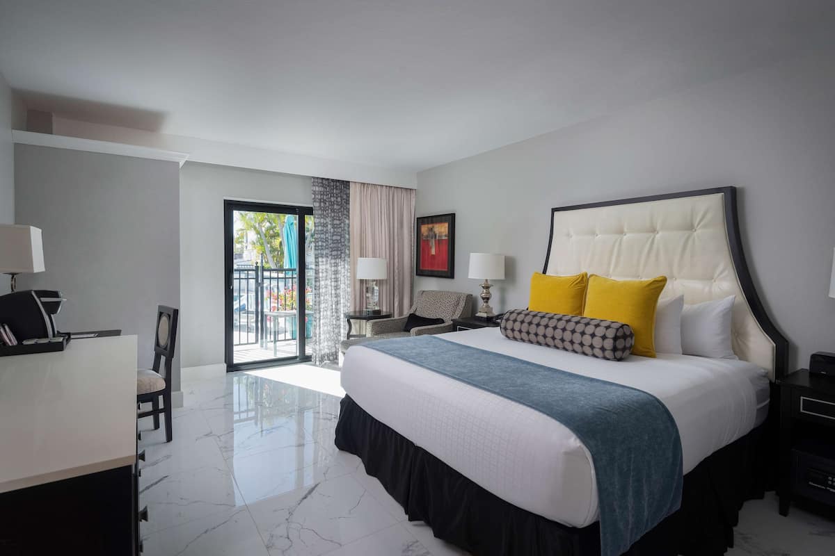 A modern hotel room with a large bed, a desk, and a chair.