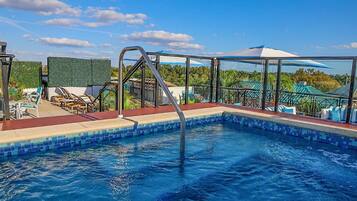 Una piscina al aire libre, sombrillas, sillones reclinables de piscina