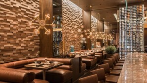Ein modernes Restaurant mit Ledersitzen und Tischen, einer Wand mit Ziegelmuster und einem Weinkühlschrank.