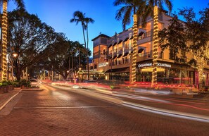A hotel with multiple floors, outdoor seating, and palm trees.