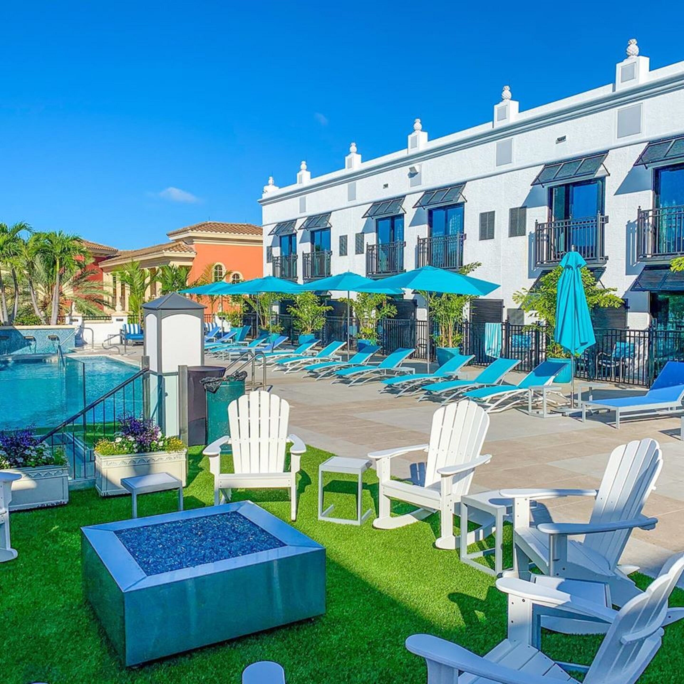 Un espace piscine d’hôtel avec des chaises longues, un jacuzzi et un bâtiment doté de balcons.