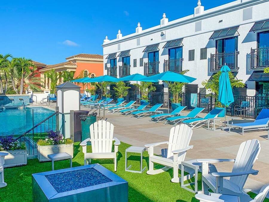Un espace piscine d’hôtel avec des chaises longues, un jacuzzi et un bâtiment doté de balcons.