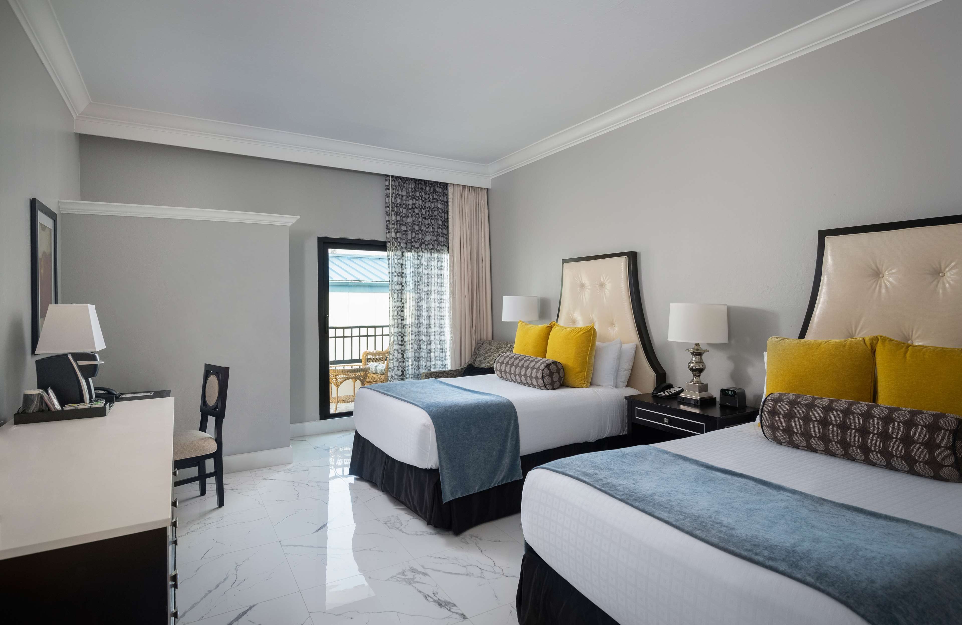 A hotel room with two beds, a desk, and a chair.