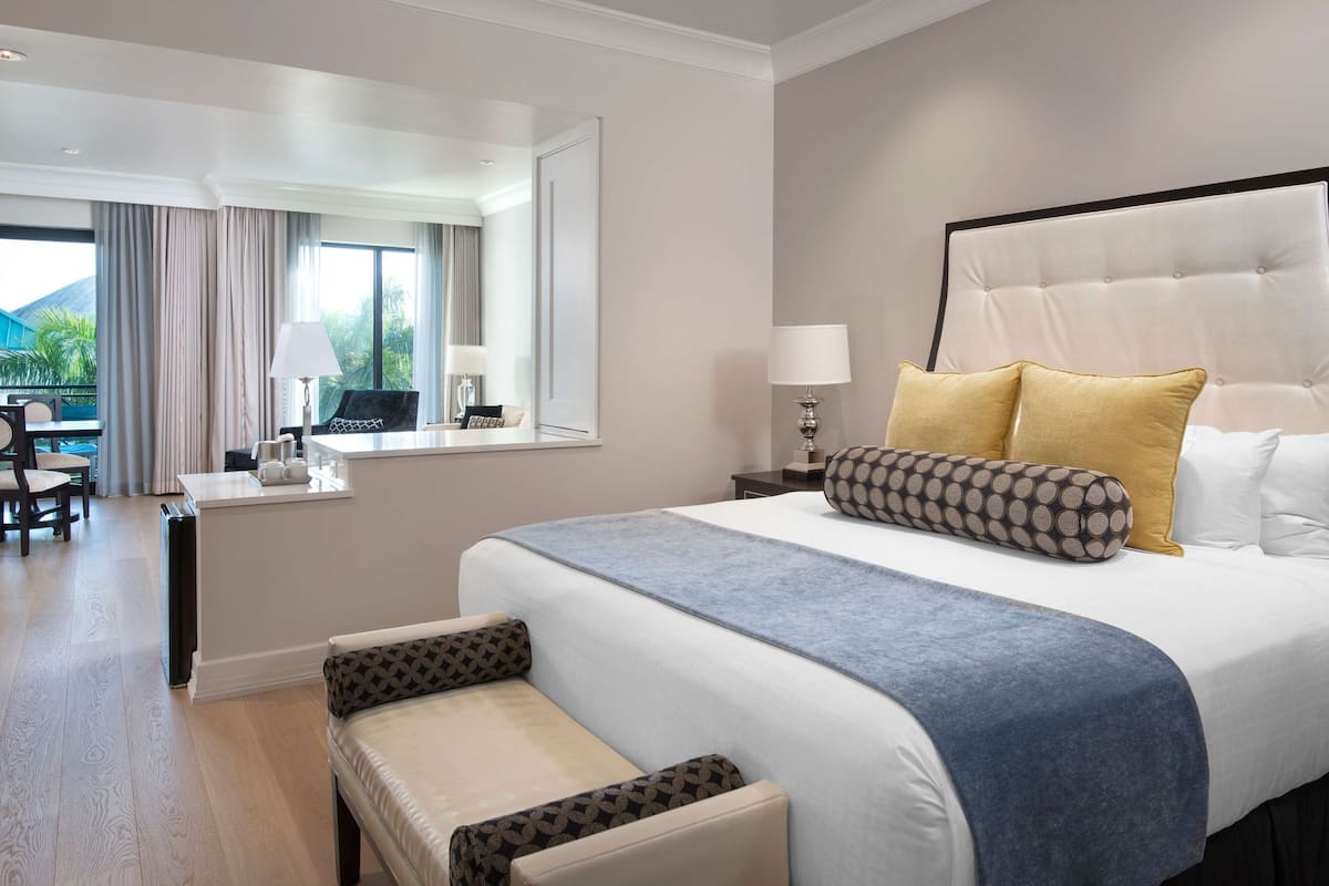A hotel room with a large bed, a desk, a chair, and a view of the outdoors.