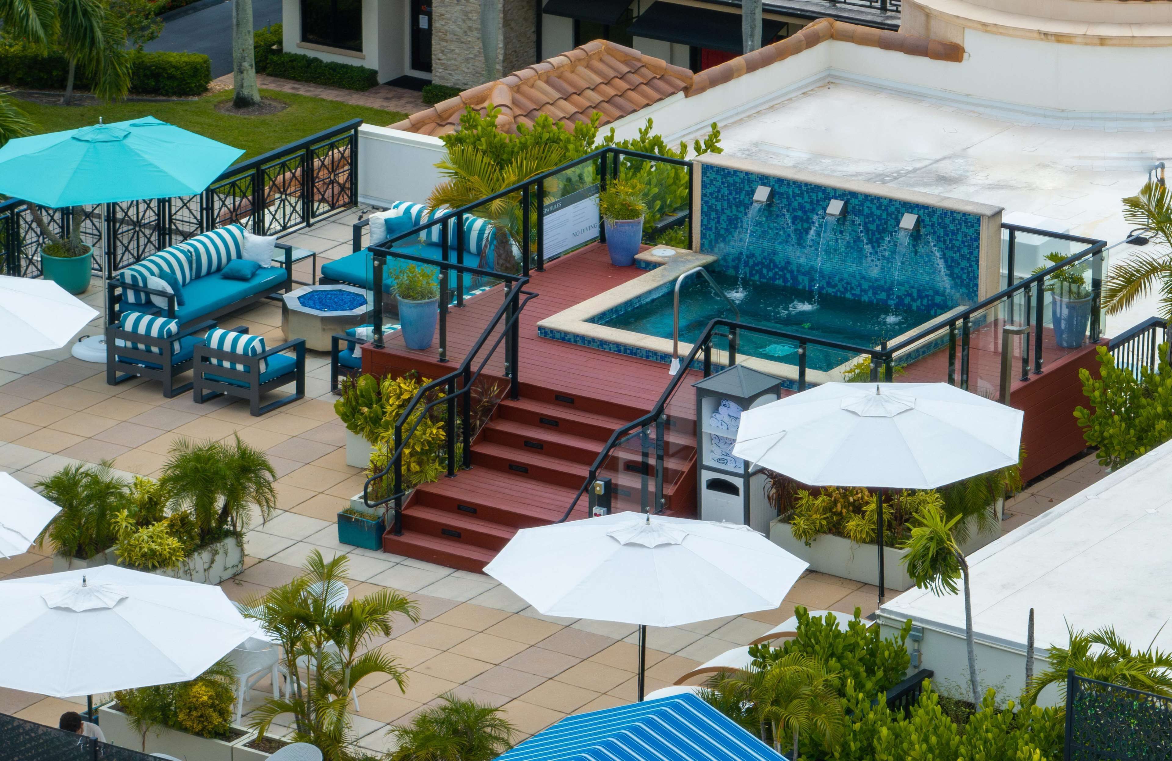 A rooftop pool area with a blue mosaic pool, outdoor seating, and stairs leading to the pool.