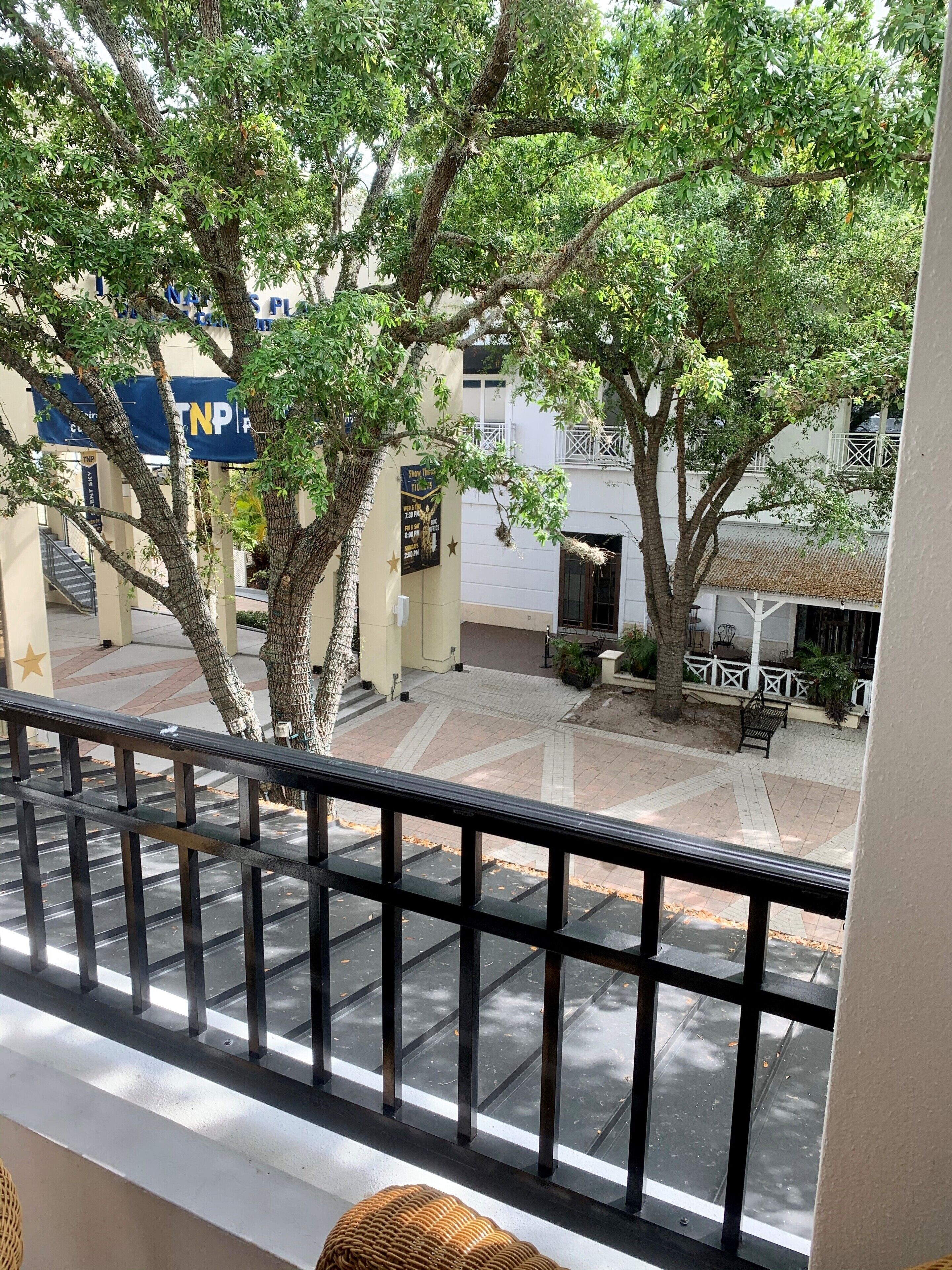 A balcony with a view of a courtyard, trees, and a building with a TNF sign.