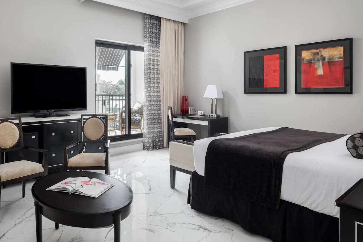 A hotel room with a bed, a TV, a desk, a chair, and a small table.
