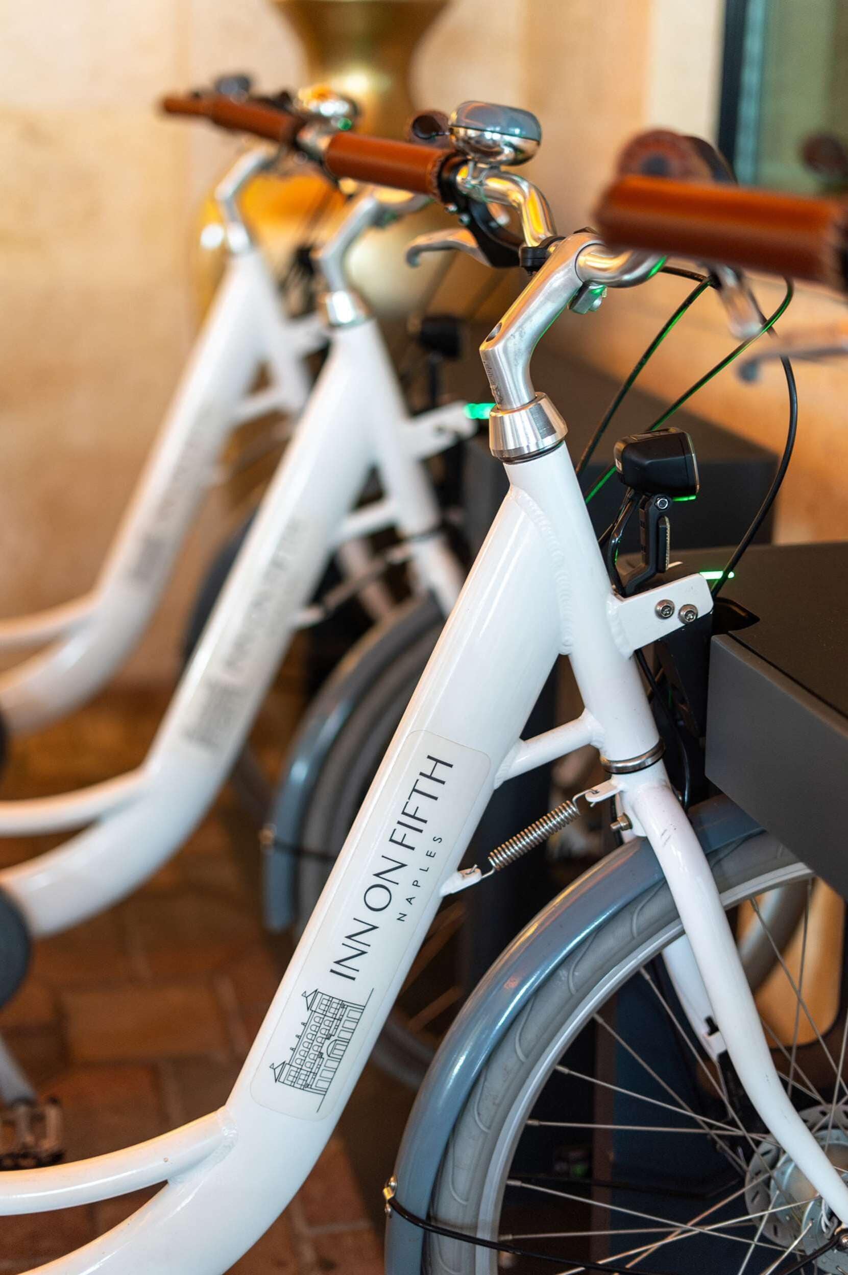 A row of white bicycles with "INN ONFIFTH" branding, indicating a rental service.
