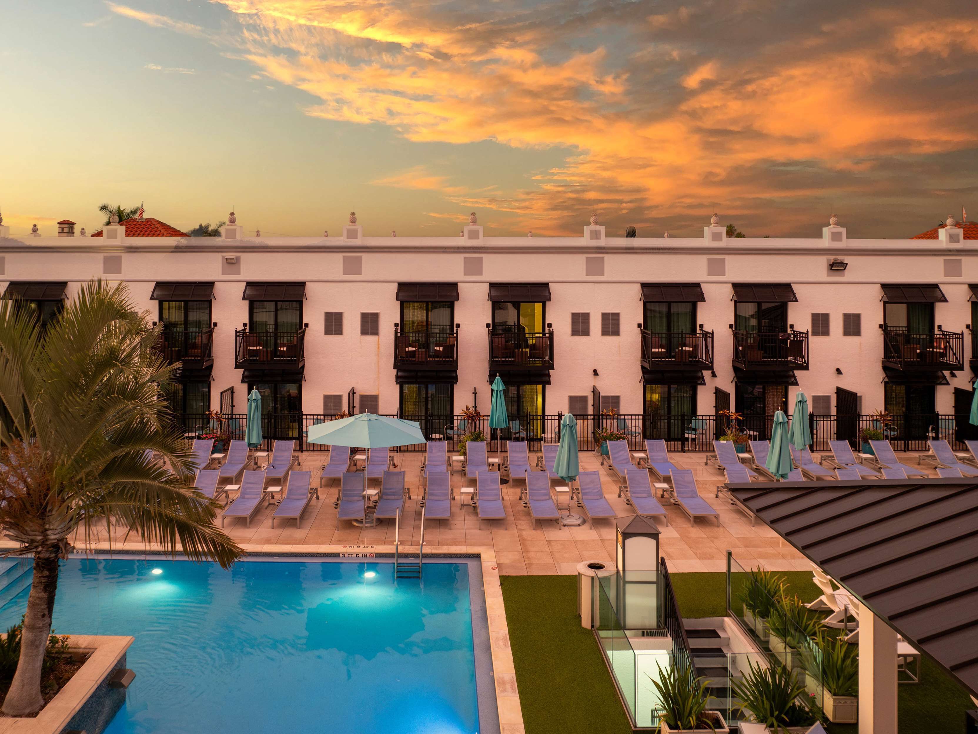 A hotel with a pool, sun loungers, and a sunset view.