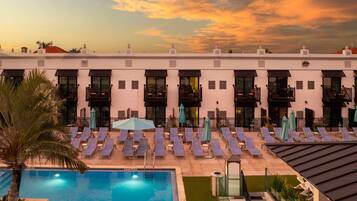 A hotel with a pool, sun loungers, and a sunset view.