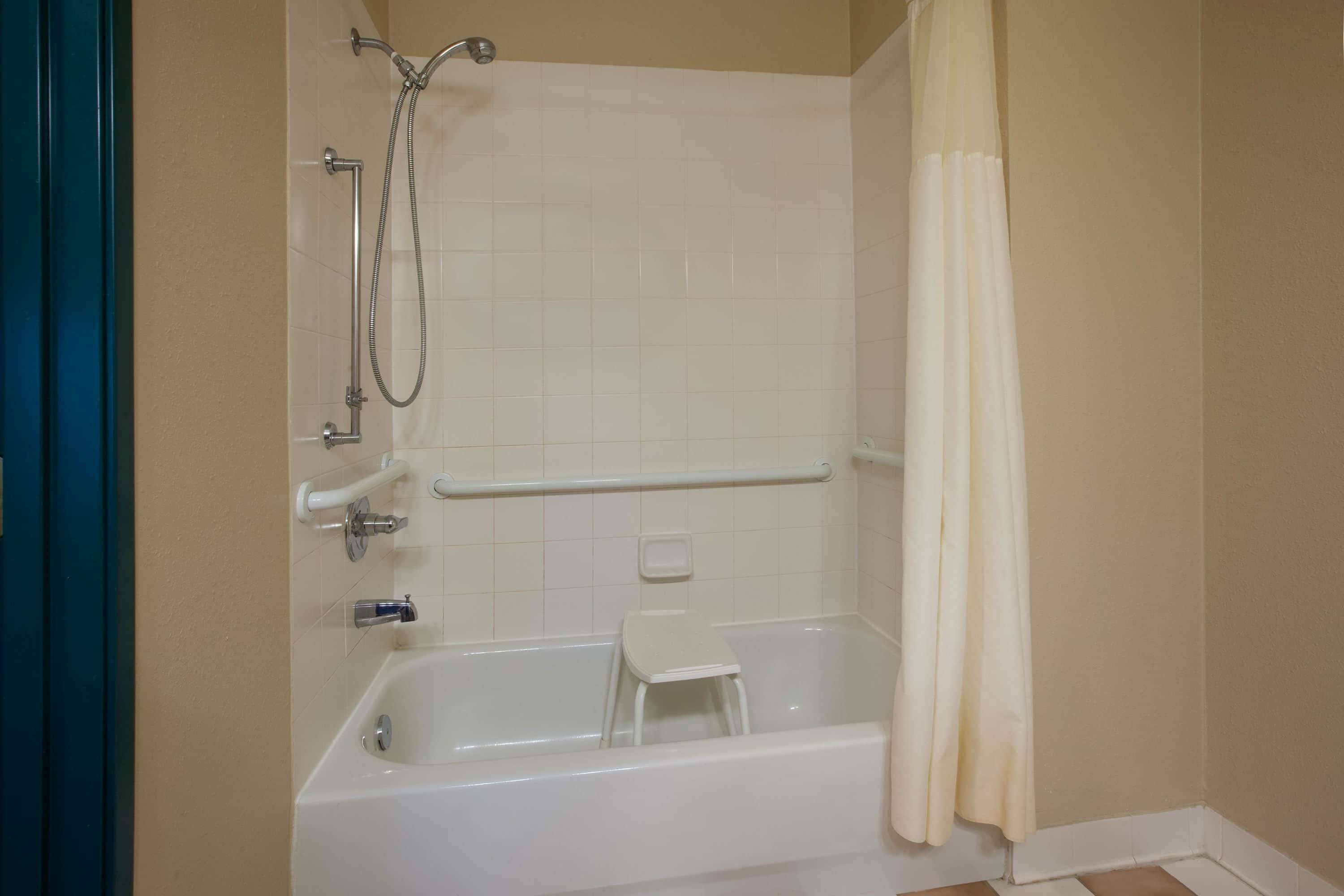 A bathroom with a bathtub, a shower, a white towel, and a white shower curtain.