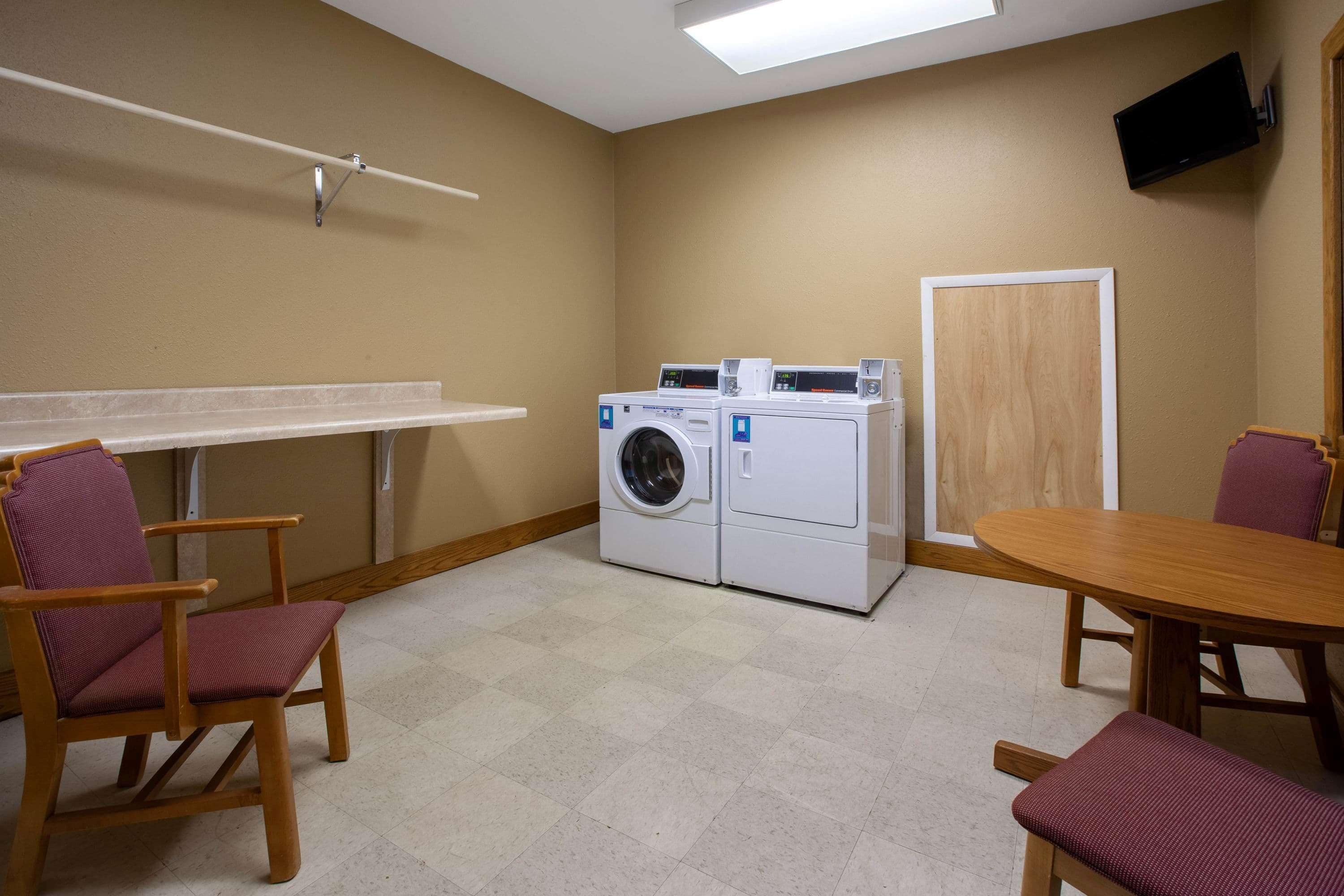 A laundry room with a washing machine, a table, and chairs.