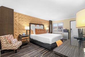 Una habitación de hotel con cama, escritorio, silla y minibar.