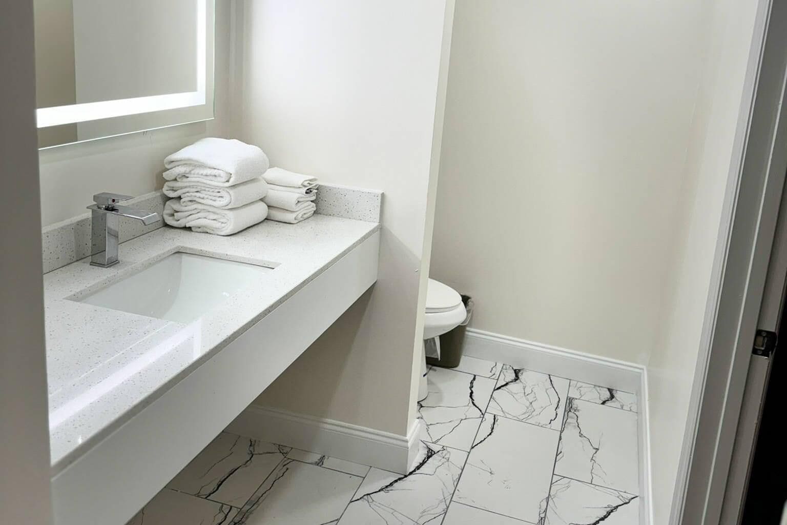 A bathroom with a white sink, a mirror, and a toilet.
