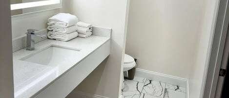 A bathroom with a white sink, a mirror, and a toilet.