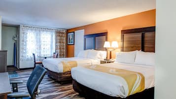 Habitación de hotel con dos camas, un escritorio, una silla y una lámpara.