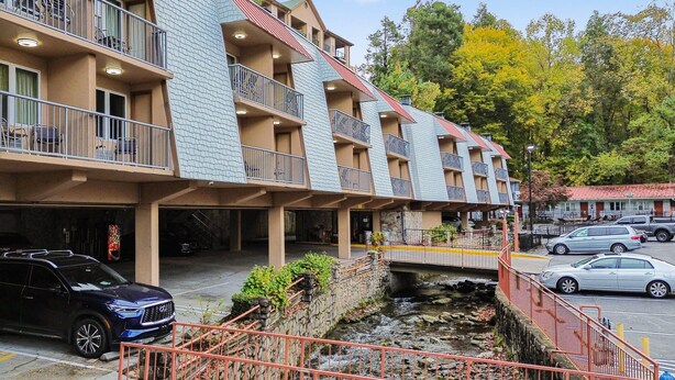 A multi-story hotel with balconies, a stone retaining wall, and a parking area. - Quality Inn Creekside - Downtown Gatlinburg (Gatlinburg)