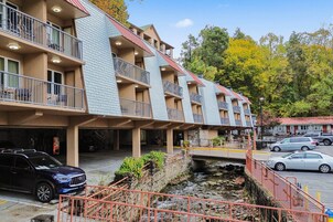 A multi-story hotel with balconies, a stone retaining wall, and a parking area.