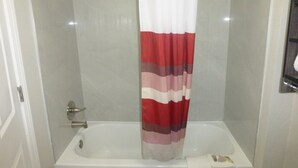 Une salle de bain avec un rideau de douche, une baignoire et un porte-serviettes.