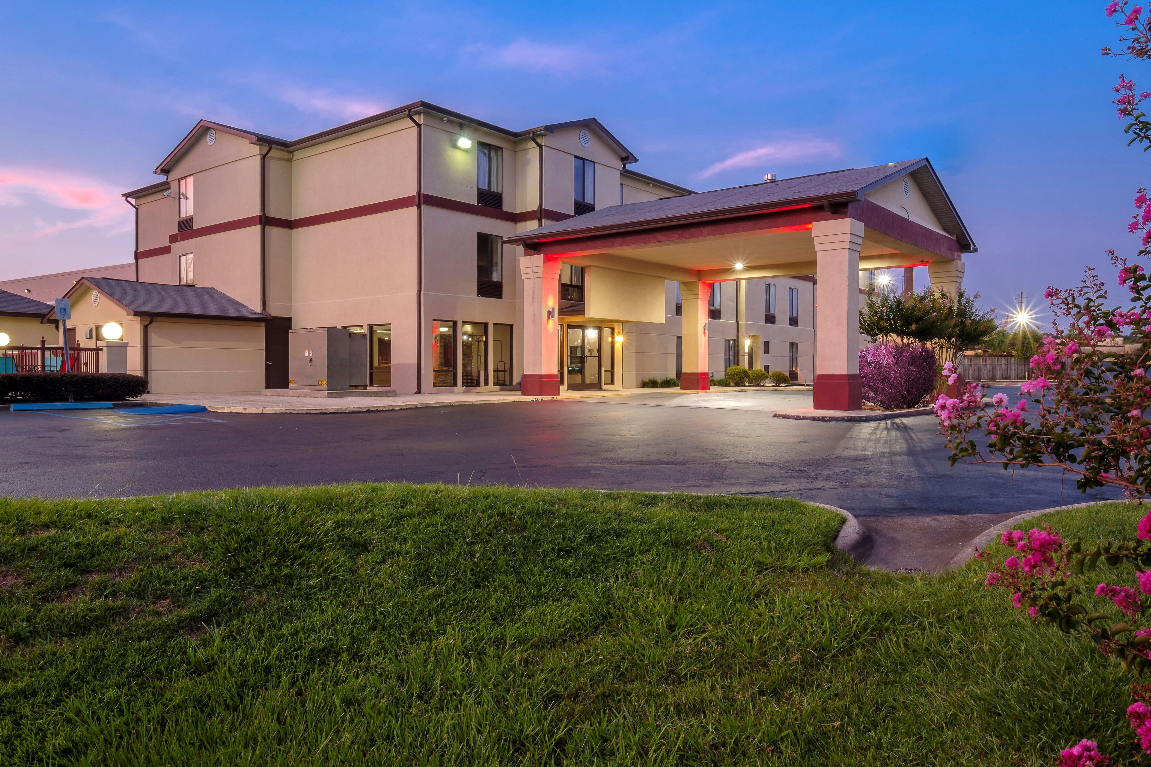 A hotel with a covered entrance, a parking lot, and a well-maintained lawn.