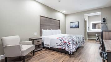 A bedroom with a bed, a chair, a nightstand, and a mirror.