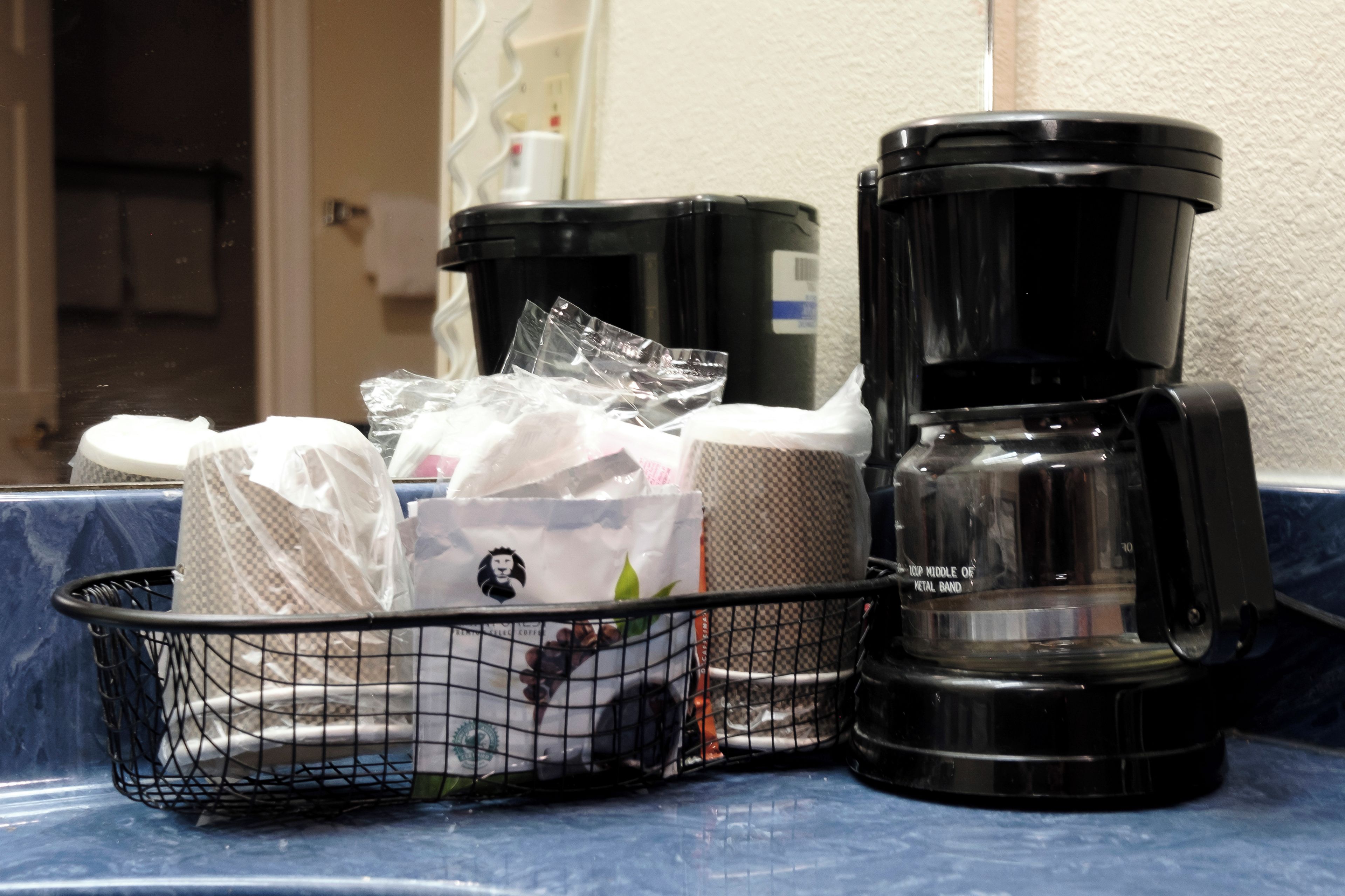 A coffee maker, a basket with coffee pods, and a coffee grinder on a countertop.
