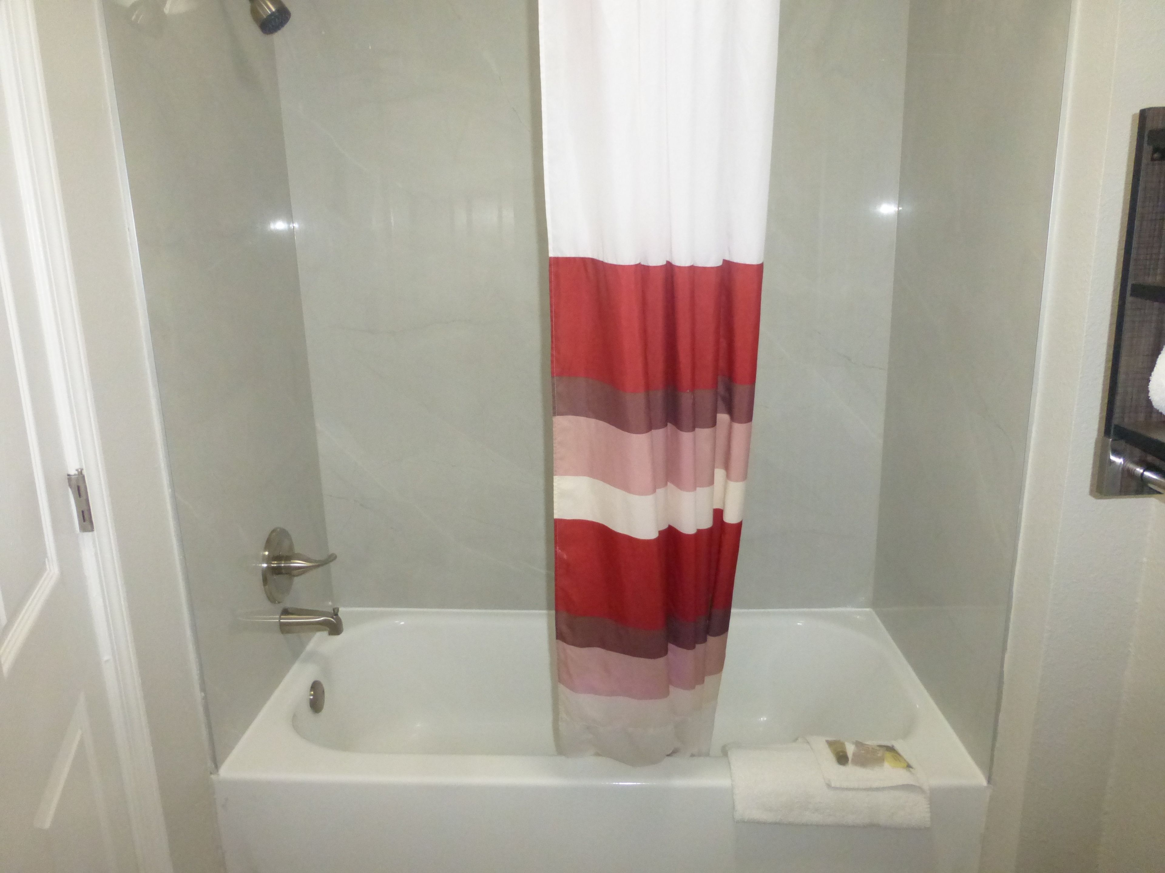 A bathroom with a shower curtain, a bathtub, and a towel rack.