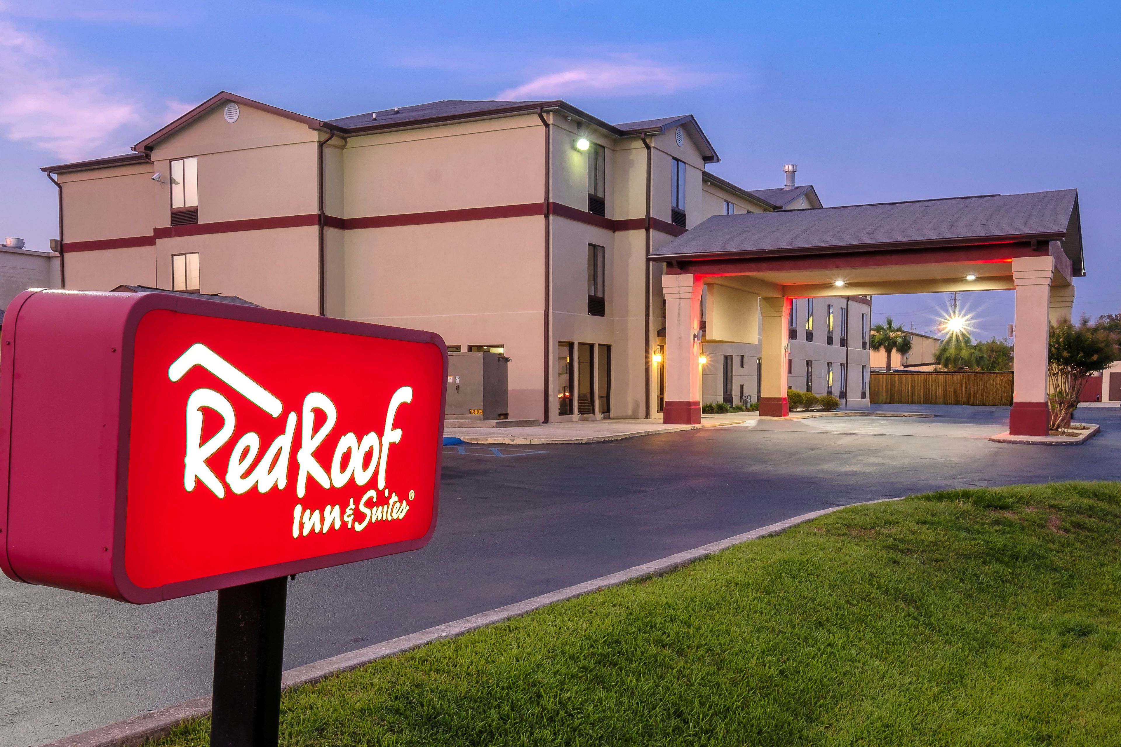 Um Red Roof Inn & Suites com entrada bem iluminada e visão clara do estacionamento.