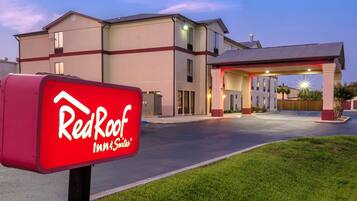 Um Red Roof Inn & Suites com entrada bem iluminada e visão clara do estacionamento.