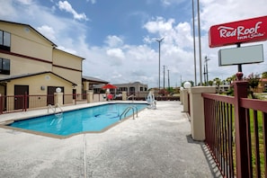 Zwembadgedeelte met een redderstoel, een Red Roof Inn & Suites bord en een omheind voetpad.