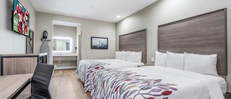 Una habitación de hotel con cama, escritorio, silla, televisor y un cuadro en la pared.