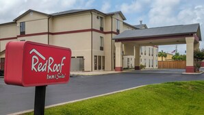 A Red Roof Inn & Suites sign in front of a building with a covered parking area. - Red Roof Inn & Suites Mobile SW – I-10 (Mobile)