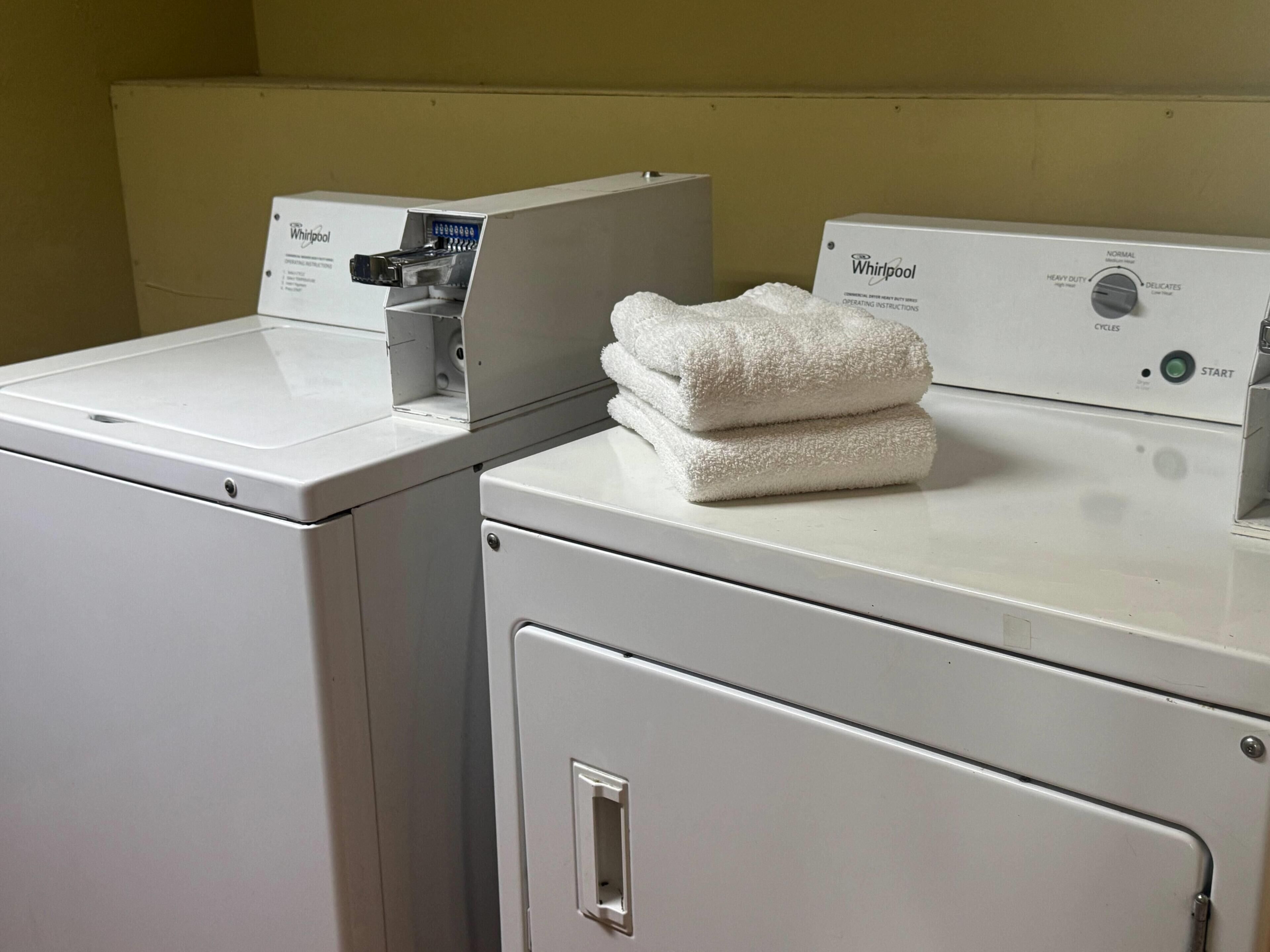 A front-loading Whirlpool washer and dryer in a laundry room with a beige wall.