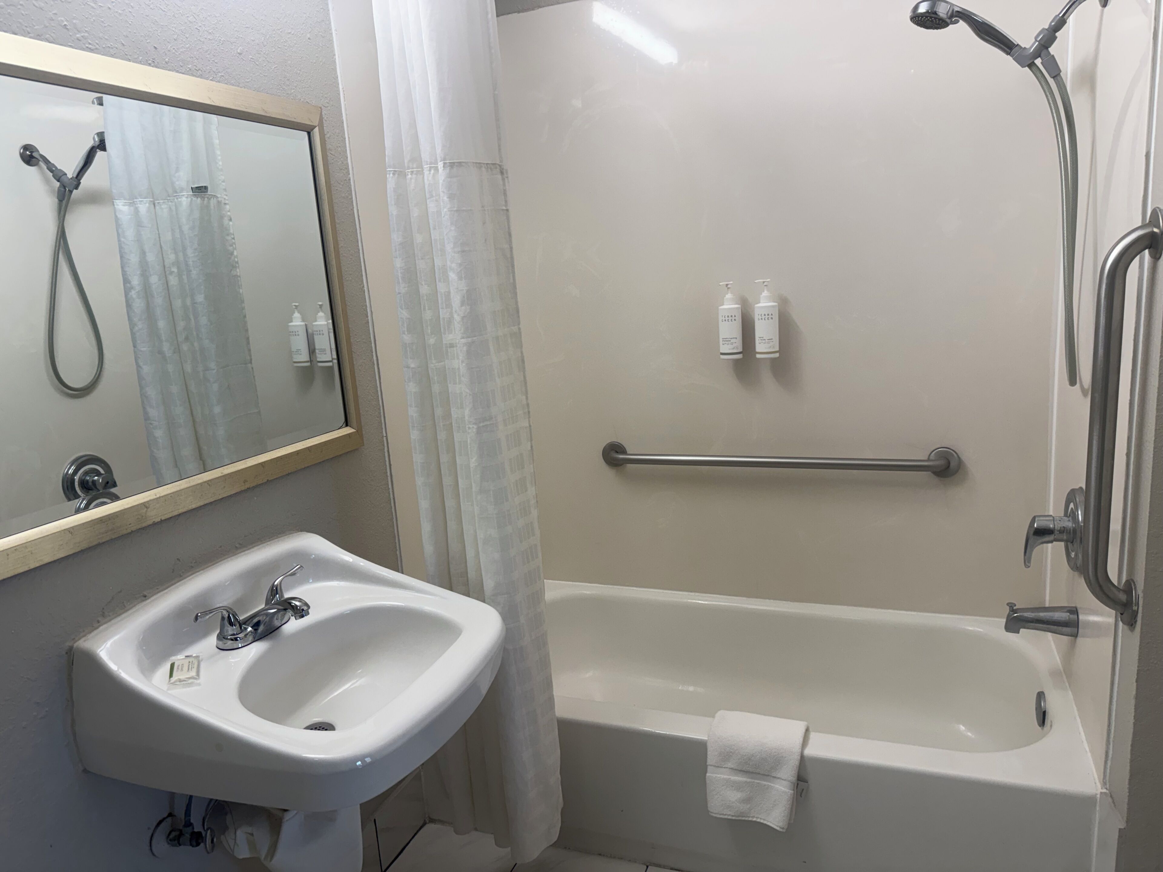 A bathroom with a sink, mirror, shower, and bathtub.