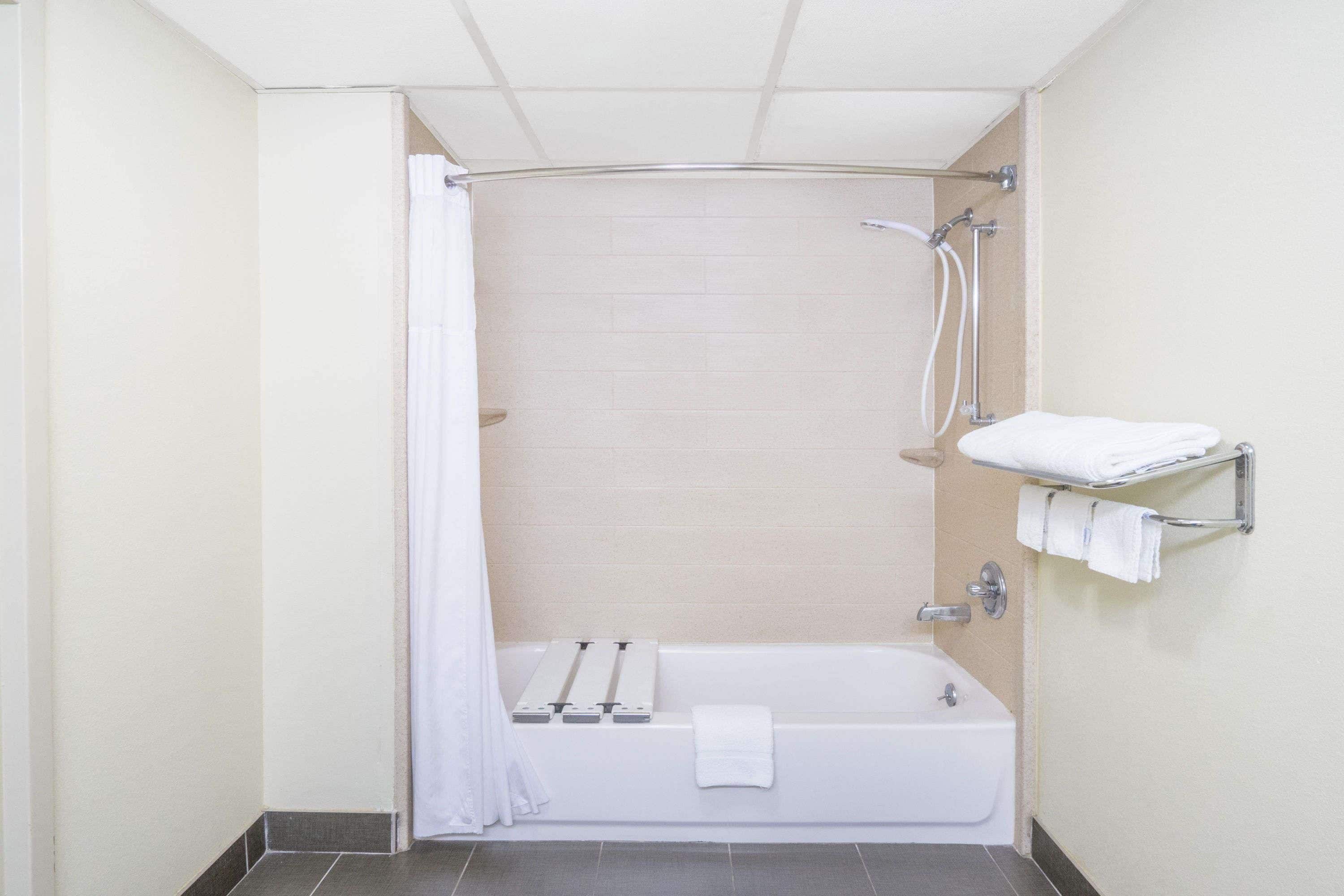A small, clean bathroom with a bathtub, a shower, and a towel rack.