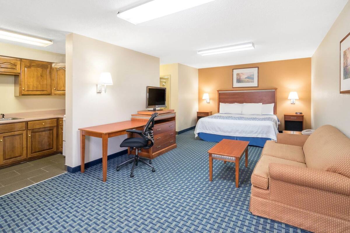 Une chambre d’hôtel équipée d’un lit, d’un bureau, d’une chaise et d’une kitchenette.