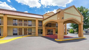 A multi-story motel with a central courtyard, outdoor seating, and a covered entrance. - Days Inn by Wyndham Oak Grove/Ft. Campbell (Oak Grove)