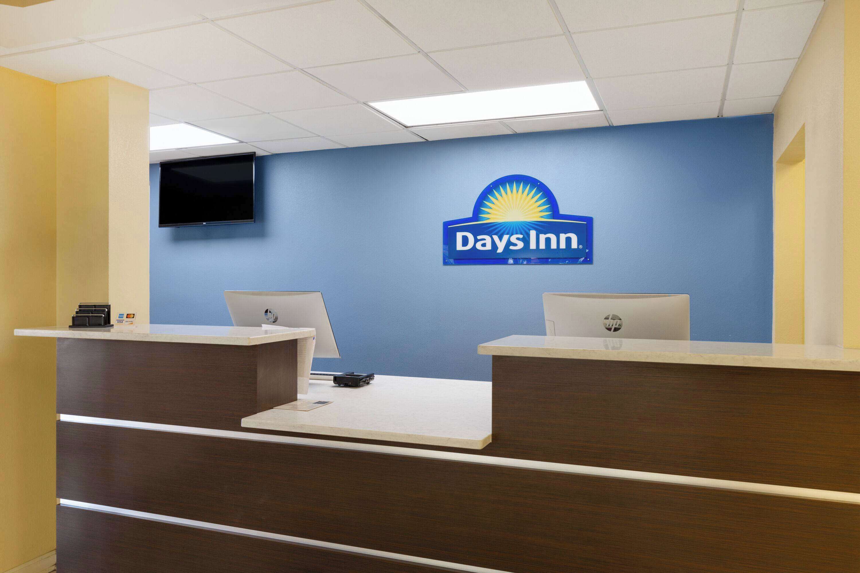 Una reception di Days Inn con una TV a schermo piatto montata a parete, due computer HP e un banco reception.